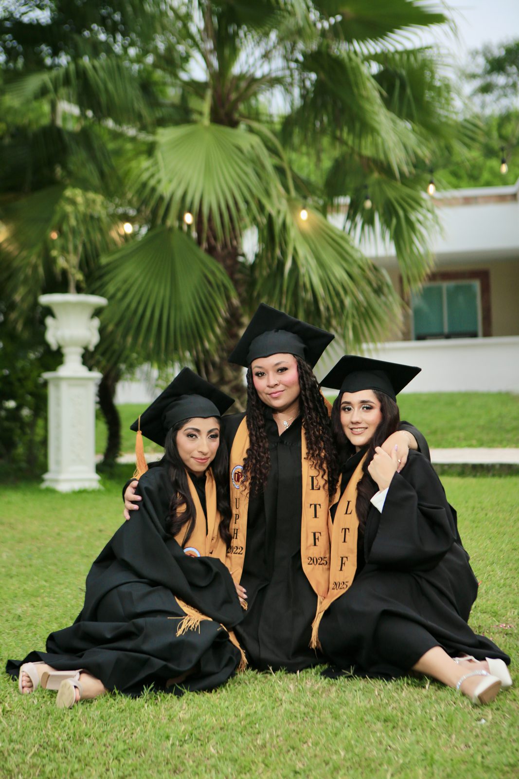 Graduadas posando en jardín con toga y birrete